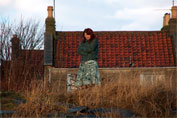 Gerry standing in the long grass with a red tiled cottage behind